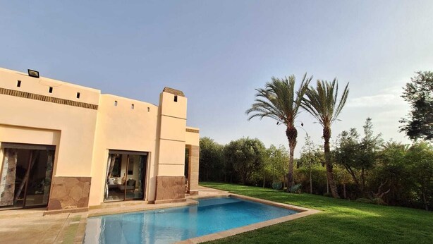 A modern house with a swimming pool, a covered patio, and a well-maintained lawn.