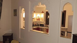 A modern kitchen with built-in appliances, a dining area with a small table and chairs, and decorative arches.