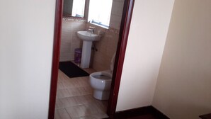 Un baño pequeño con inodoro, lavamanos y espejo.