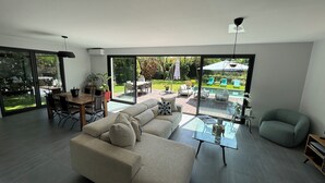 A modern living room with a large glass door leading to a patio area. - Villa Saint-paul-de-vence With Swimming Pool (Saint-Paul-de-Vence)