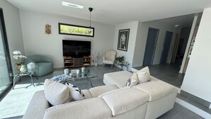 A modern living room with a sectional sofa, a flat-screen TV, and a glass coffee table. - Villa Saint-paul-de-vence With Swimming Pool (Saint-Paul-de-Vence)