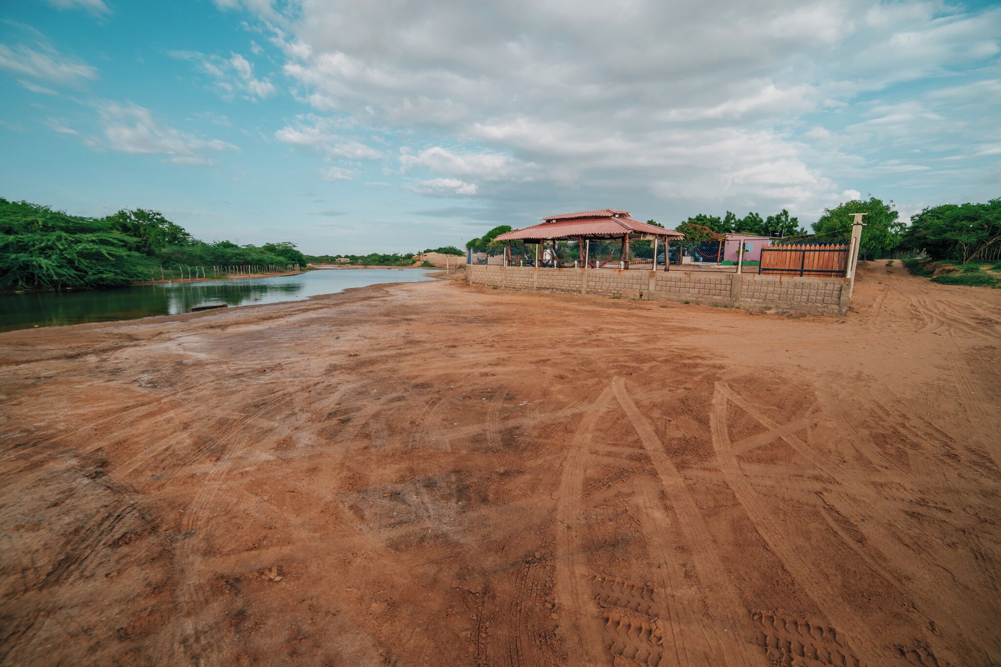 A sandy beach with a small structure and a fence.