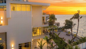 Un hôtel moderne à plusieurs étages, doté de grandes fenêtres et offrant une vue sur la plage.