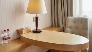 A hotel room with a wooden desk, a lamp, a tissue box, and two bottles of water. - Vienna 3 Best Hotel (Shanghai Qiantan Expo Sanlin) (Shanghai)