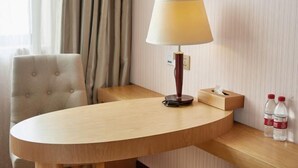 A hotel room with a round wooden table, a lamp, a tissue box, and two bottles of water. - Vienna 3 Best Hotel (Shanghai Qiantan Expo Sanlin) (Shanghai)