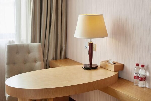 A hotel room with a round wooden table, a lamp, a tissue box, and two bottles of water. - Vienna 3 Best Hotel (Shanghai Qiantan Expo Sanlin) (Shanghai)