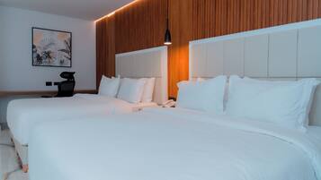 Una habitación de hotel moderna con dos camas grandes, un panel de madera, una obra de arte colgada y un escritorio con una silla.