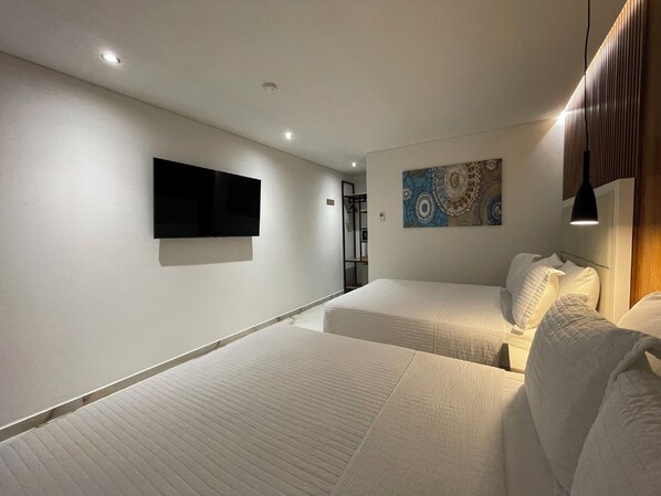 A modern hotel room with two beds, a flat-screen TV mounted on the wall, and a decorative wall piece. - Hotels 111 (San Andrés)