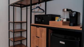 Una kitchenette compacta con microondas, cafetera y un refrigerador pequeño.