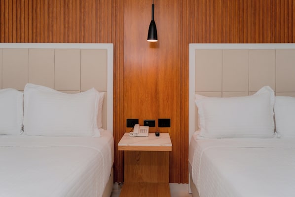 A hotel room with two beds, a wooden headboard, a bedside table with a phone, and a pendant light. - Hotels 111 (San Andrés)
