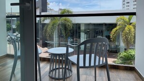 A balcony with a glass wall, modern furniture, and a view of the cityscape. - Hotels 111 (San Andrés)