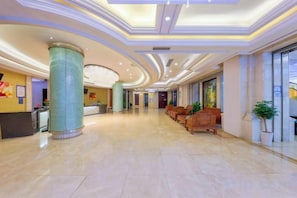 Un vestíbulo de hotel con mostrador de recepción, zona de estar y un pilar grande.
