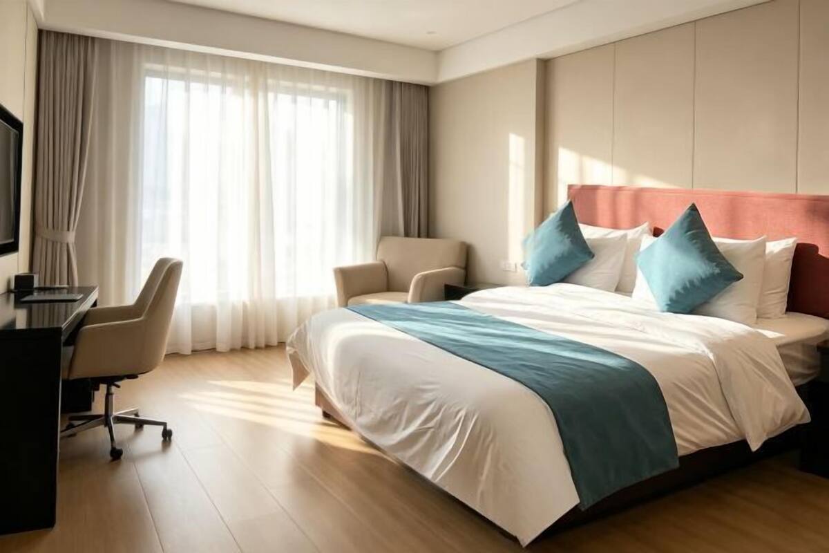 A hotel room with a bed, a desk, a chair, and a television.