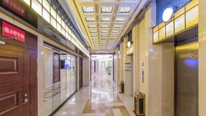 A corridor with a polished floor, a wooden door on the left, and an elevator on the right. - Hangzhou Fuyang Yaoyue International Hotel (Enbo Avenue) (Hangzhou)