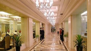 A hotel corridor with chandeliers, potted plants, and a checkered floor. - Hangzhou Fuyang Yaoyue International Hotel (Enbo Avenue) (Hangzhou)