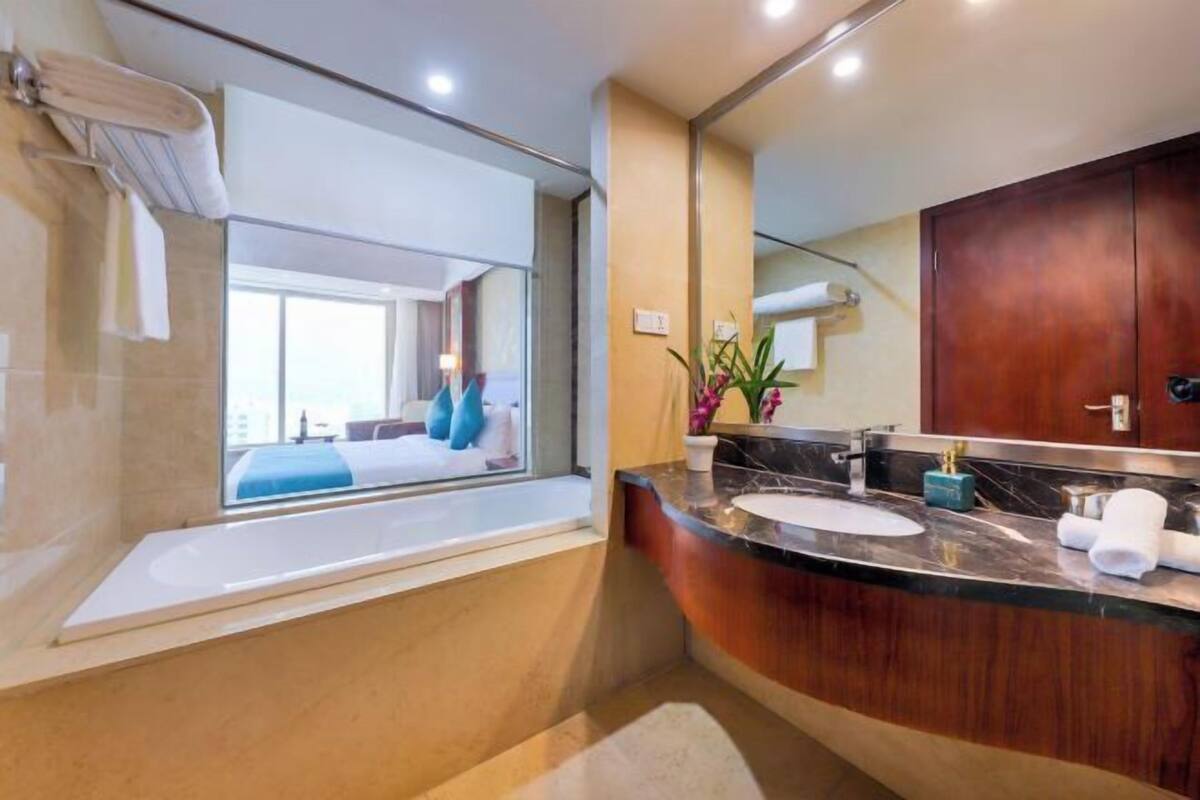 A modern bathroom with a large mirror, a bathtub, and a vanity with a sink.