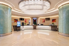 Egy szállodai előcsarnok, amelyben recepciós pult, nagyméretű csillár és modern dizájn található.