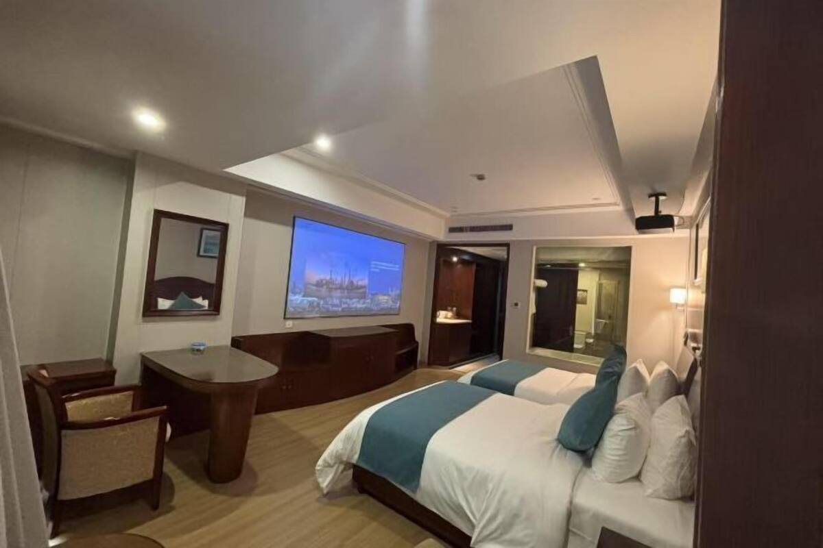 A hotel room with a bed, a desk, a chair, a television, and a large window.