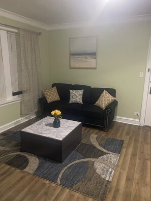 A living room with a dark-colored sofa, a marble coffee table with a vase of yellow flowers, and patterned rugs on the floor. - Charming 2-bedroom apartment in awesome Chicago with WiFi, AC (Chicago)