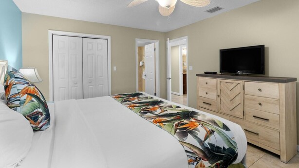 A bedroom with a bed, a television on a dresser, and a ceiling fan. - Family-Friendly 2BR w/ Views, Pool, & Beach (Tavernier)