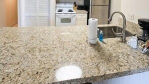 A kitchen with granite countertops, stainless steel appliances, and a clock on the wall. - Couples' Retreat 2BR w/ Ocean Views, Pool & Beach (Tavernier)