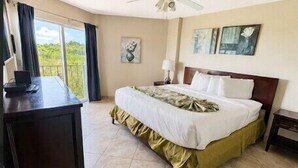 A hotel room with a bed, a desk, a ceiling fan, and a window with curtains. - Couples' Retreat 2BR w/ Ocean Views, Pool & Beach (Tavernier)