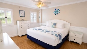 A bedroom with a bed, a dresser, a nightstand, a ceiling fan, and a wall decoration. - 2BR Condo w/ Ocean Views, Tropical Landscaping, Pool (Tavernier)