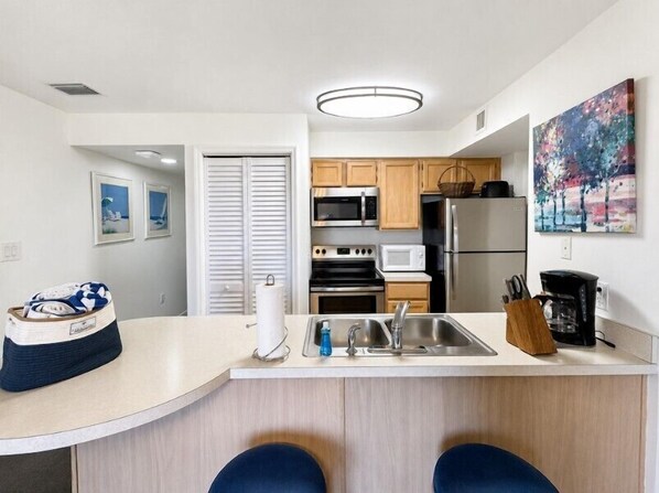 Une cuisine moderne avec un îlot central, des appareils en acier inoxydable et un tableau accroché au mur.