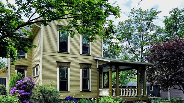 A two-story house with a porch, surrounded by a well-maintained garden with various plants and flowers.