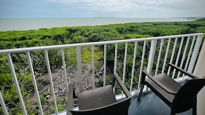 Ein Balkon mit zwei Stühlen und Blick auf das Meer und viel Grün.