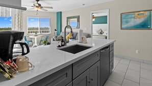 A modern kitchen with a large island, a ceiling fan, and a view of the outdoors.