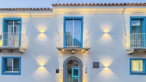 Fachada de hotel con un cartel que dice "LUMA Relais de Charme", con balcones con barandillas blancas y ventanas con marcos azules.