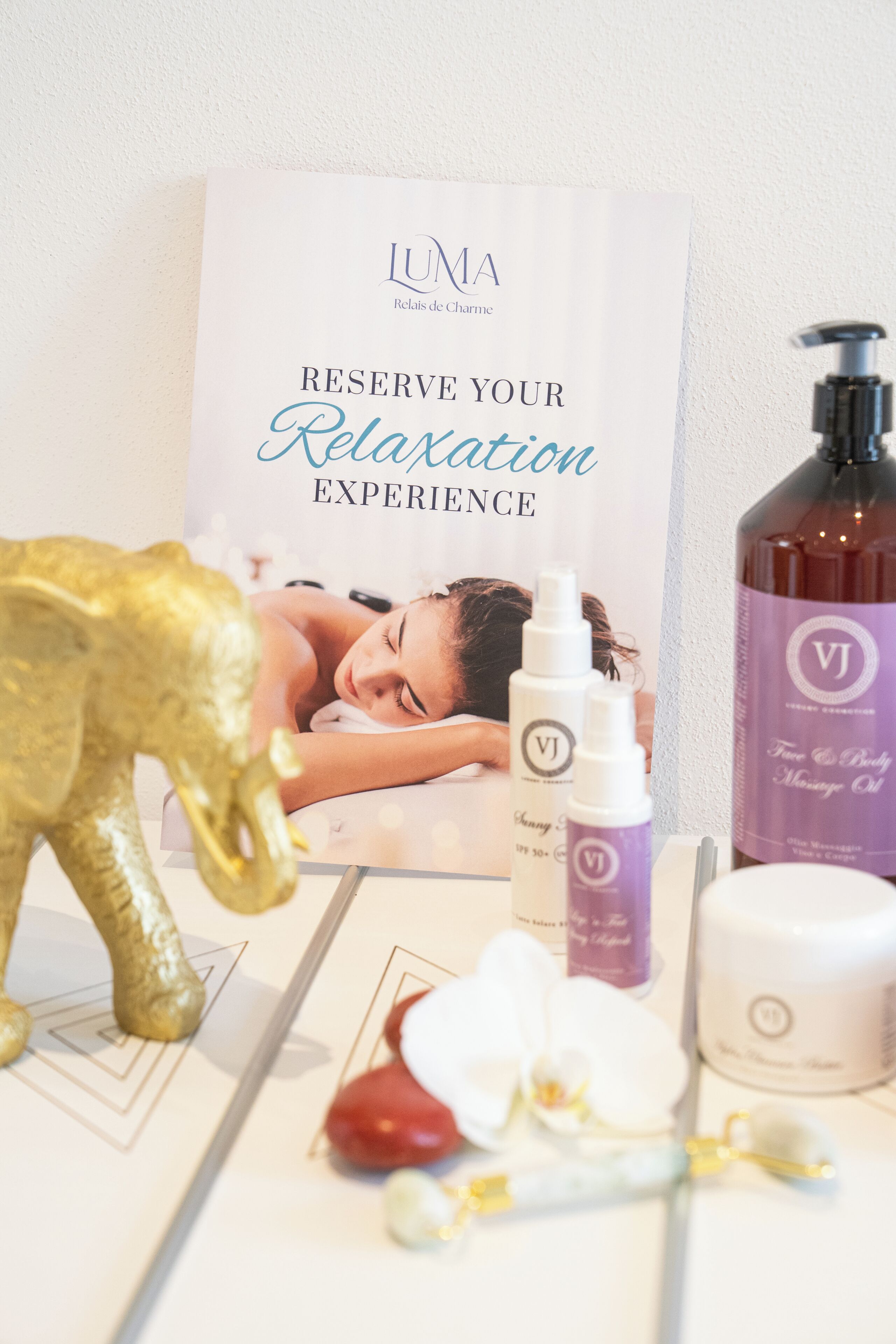 A spa setting with a relaxation poster, massage oil bottles, a massage table, and a decorative elephant.