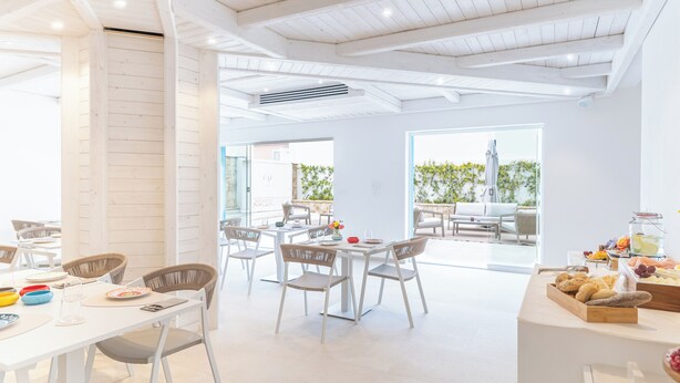 Un comedor amplio y luminoso con mobiliario blanco y vistas al exterior.