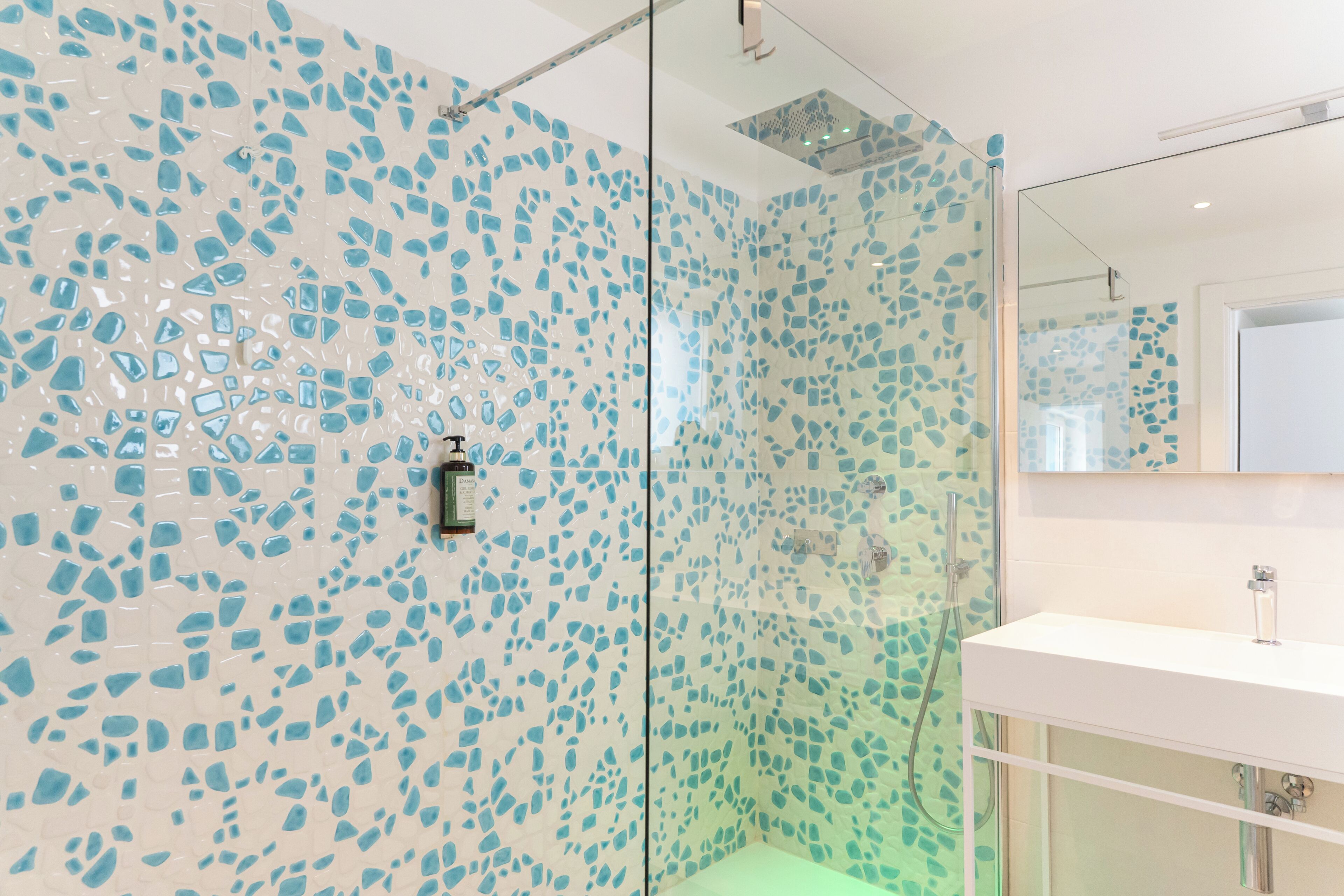 A bathroom with a glass shower enclosure and a white sink.