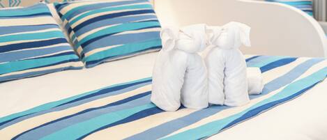 A hotel room with a bed featuring striped bedding, a white headboard, and neatly arranged towels.