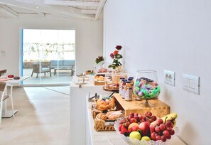 A breakfast buffet with various food items and a vase of flowers.