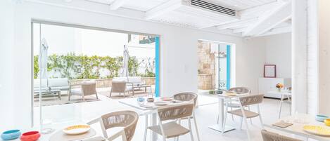 A bright, open-plan dining area with modern furniture and large windows.