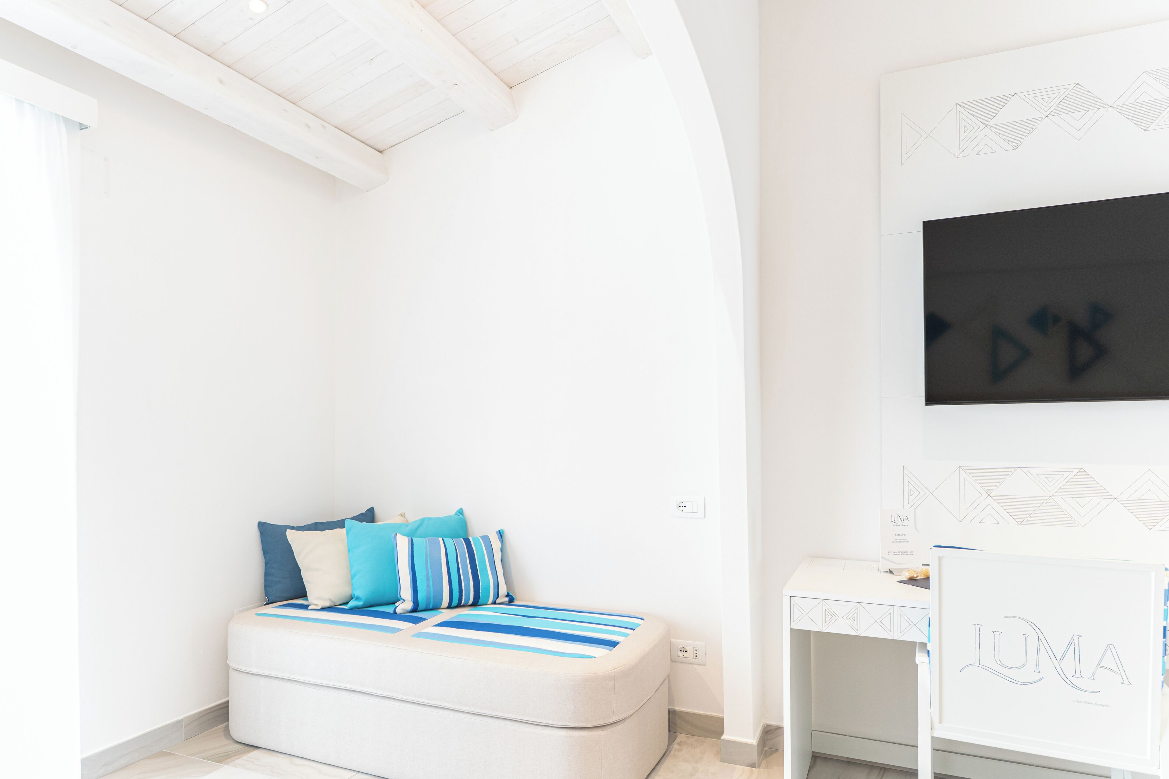 Une chambre moderne avec un lit, un bureau et un téléviseur fixé au mur.