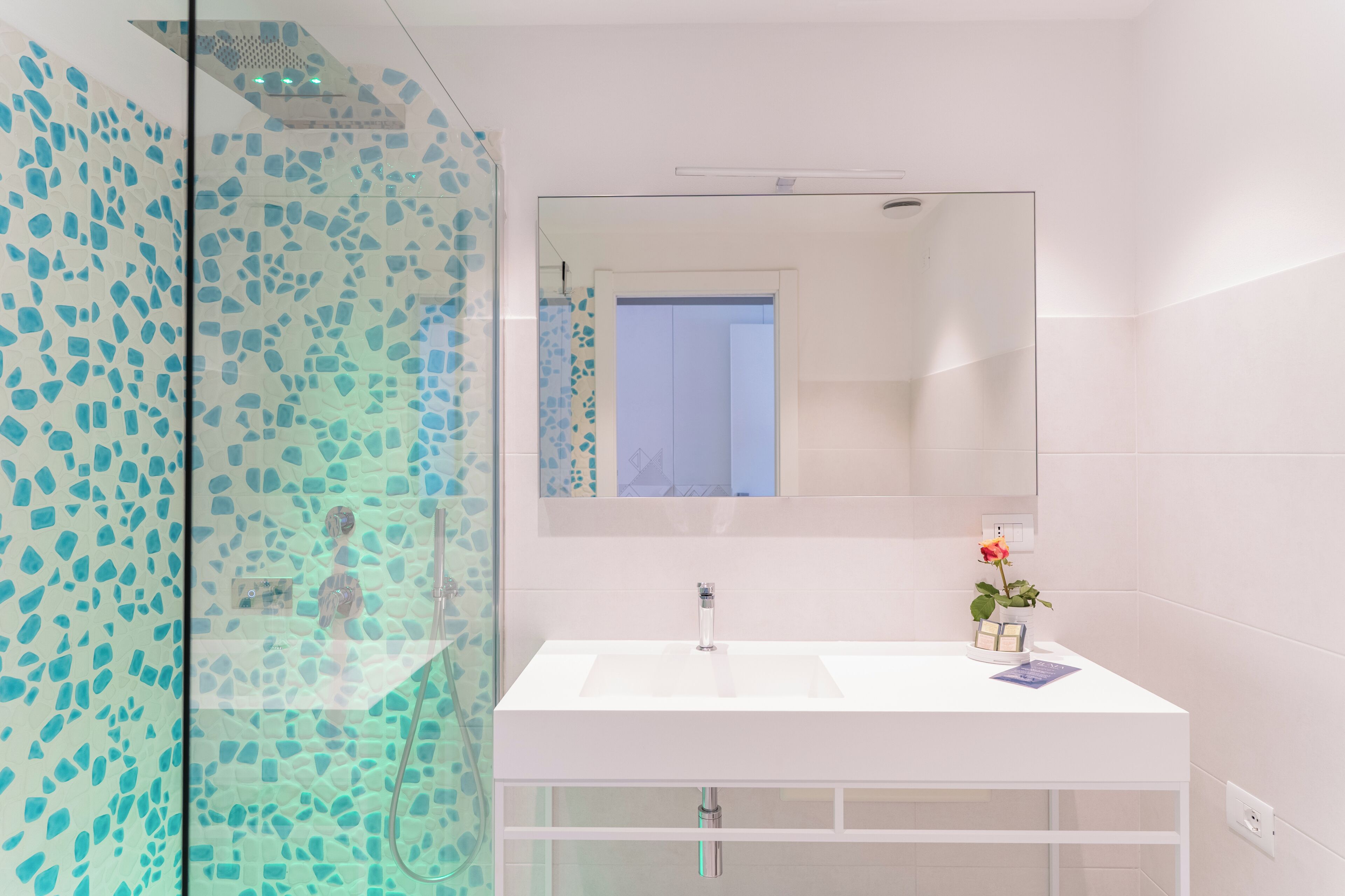 A modern bathroom with a glass shower enclosure, a white sink, and a large mirror.