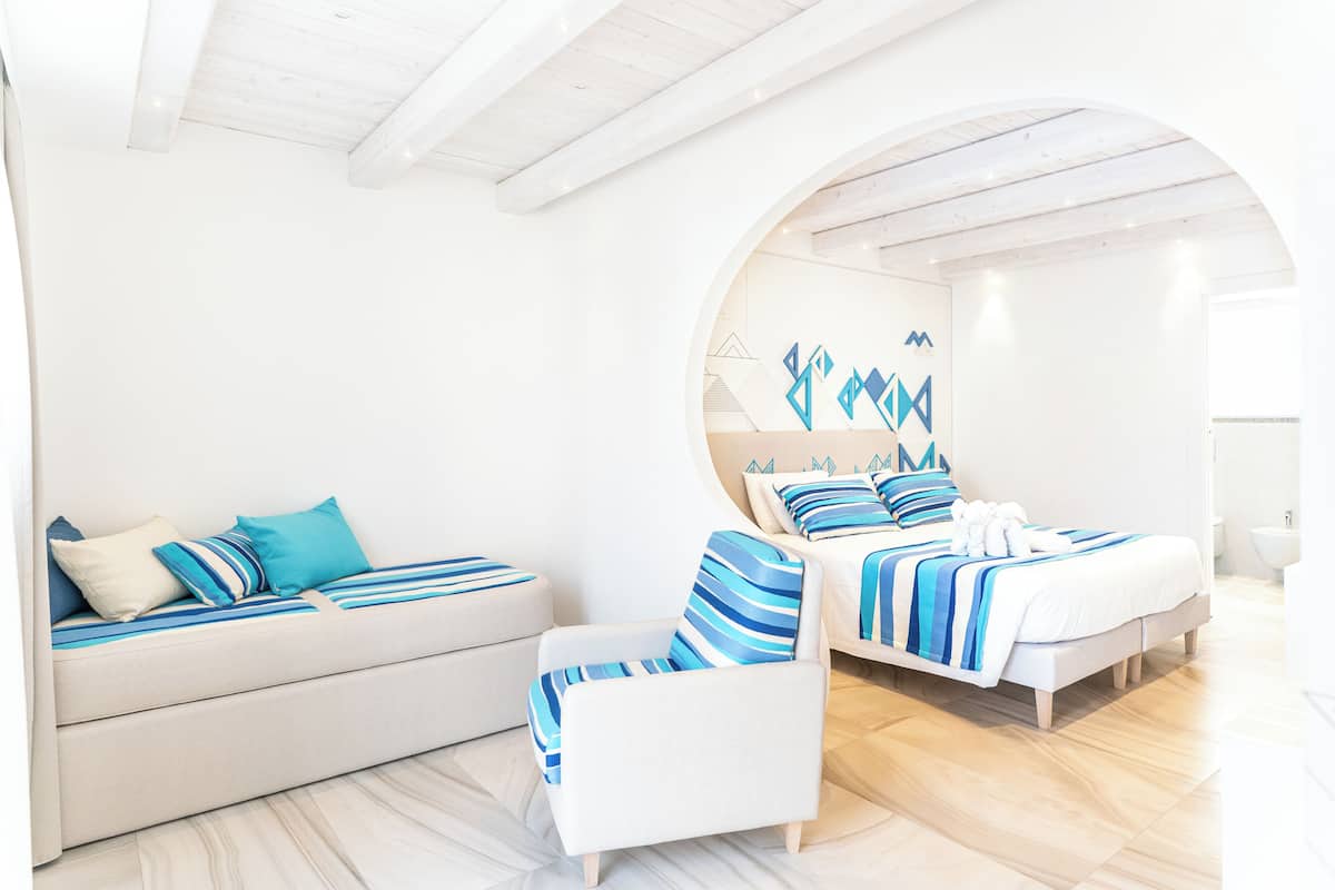 A modern bedroom with a sofa, a chair, and a bed, all in a coordinated color scheme.
