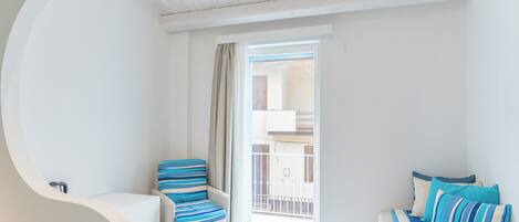A bedroom with a bed, a chair, and a balcony.