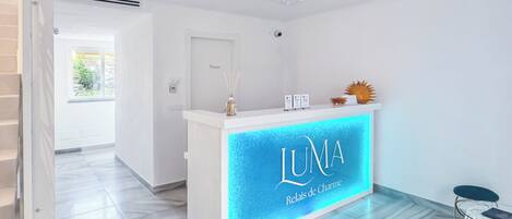 A reception desk with a blue illuminated sign reading "LUNA Relais de Charmers."