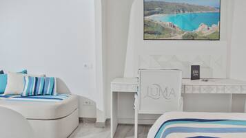 Un dormitorio moderno con cama, escritorio y televisor mostrando un paisaje costero.