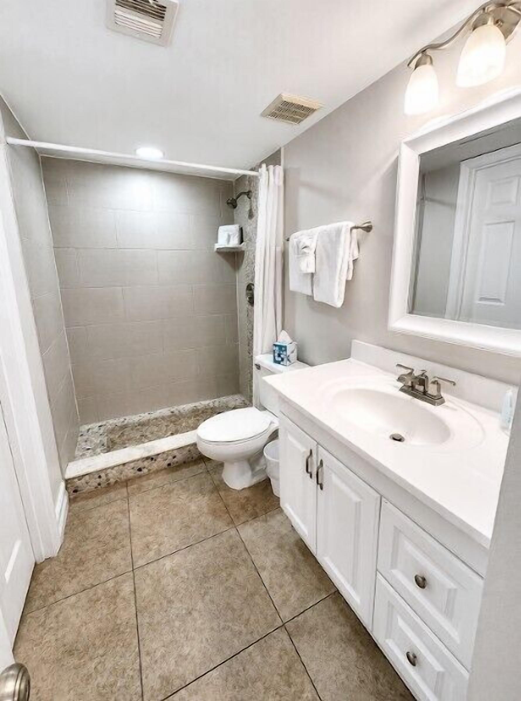 Une salle de bain comprenant des toilettes, un lavabo et un espace douche.