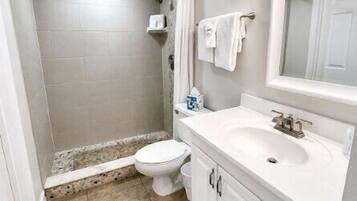 Une salle de bain comprenant des toilettes, un lavabo et un espace douche.