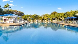 A clear swimming pool with lounge chairs and umbrellas, surrounded by palm trees and a clear sky. - Family 2BR w/ Ocean View, Pool & Tropical Setting (Tavernier)