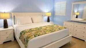 Un dormitorio con cama, mesitas de noche, cómoda, ventilador de techo y espejo.