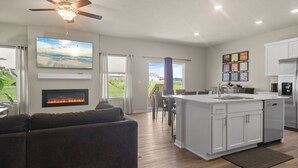 A modern kitchen with a central island, a dining area with a view, and a cozy living room with a fireplace.
