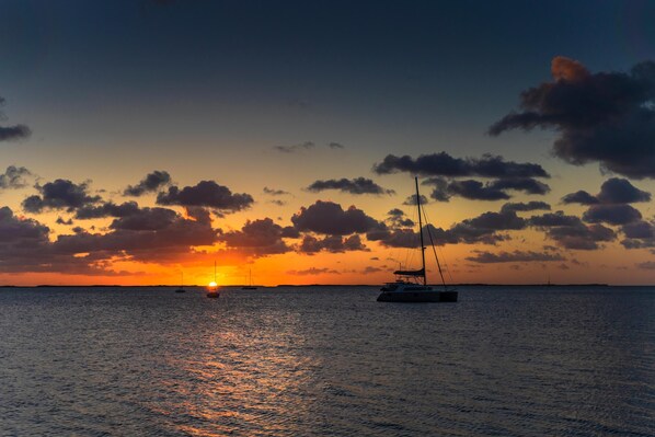 A sunset over a calm sea with boats.